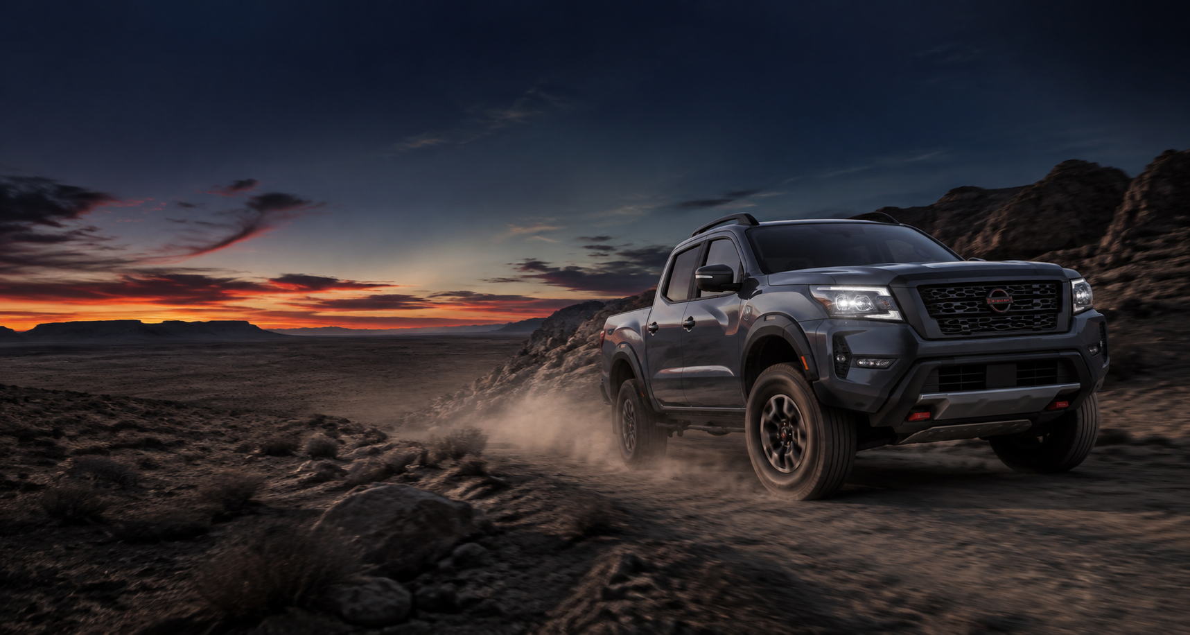 Nissan Frontier driving on a desert trail at dusk